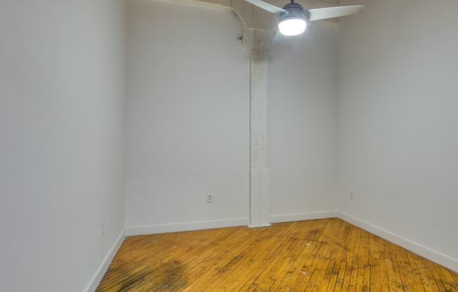 an empty room with hardwood floors and a ceiling fan