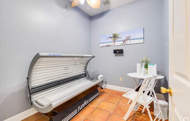 A tanning bed is in a room with a small table and chairs.