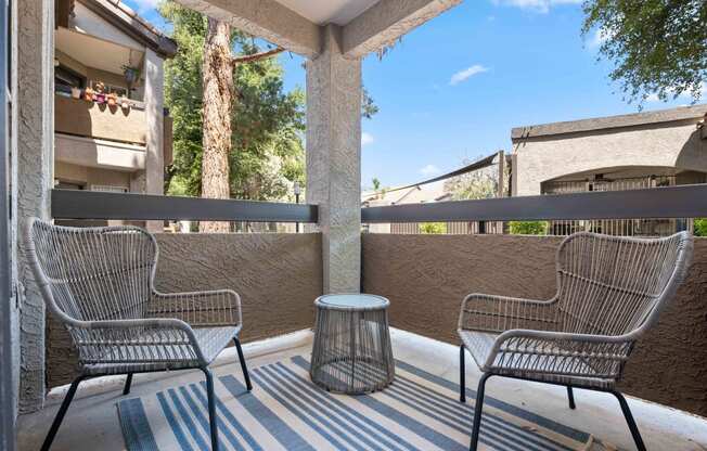 a patio with two chairs and a table on a balcony