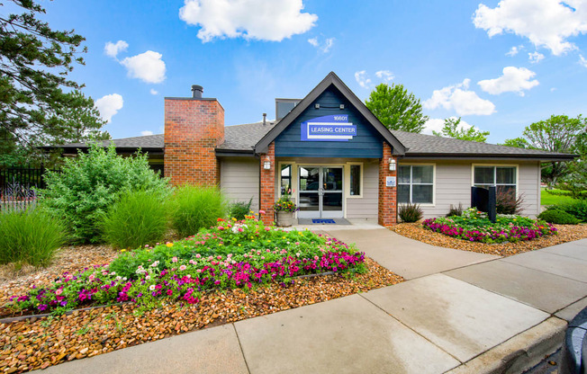 The front the leasing office with colorful flowers and greenery at Greensview Apartments in Aurora, CO