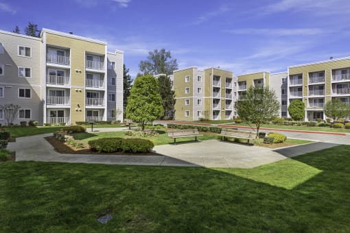 an exterior view of an apartment complex with green grass and trees  at Camelot Apartment Homes, Everett, WA, 98204