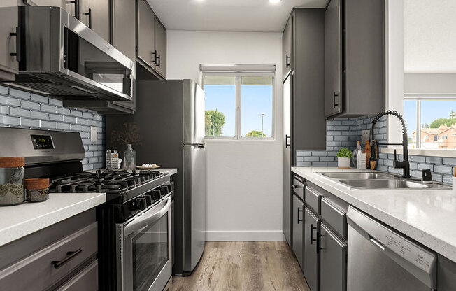 Tiled kitchen with stainless steel microwave, oven, and fridge.