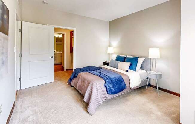 A bedroom with a bed, two lamps, and a carpeted floor.