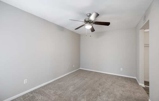 an empty room with a ceiling fan and a carpet