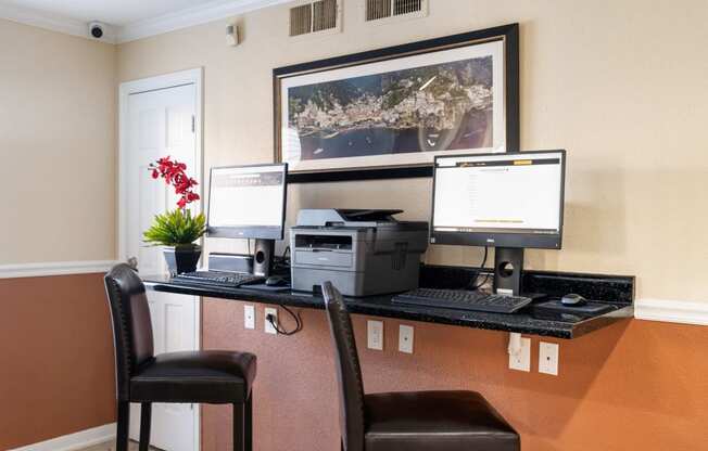 a desk with three computer monitors and a printer on it