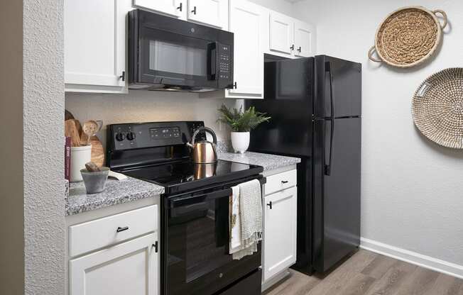 our apartments offer a kitchen with black appliances and white cabinets