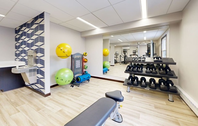 a gym with weights and a yellow ball on the wall