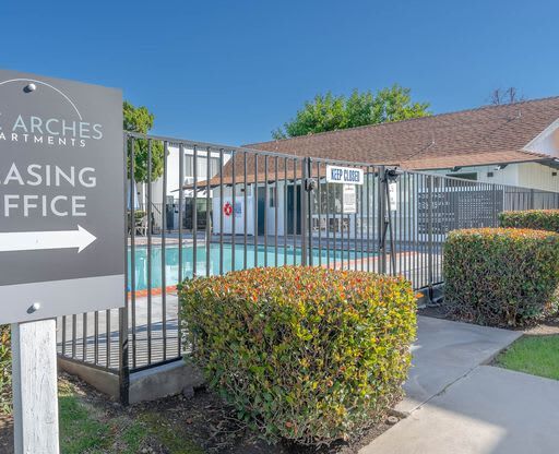 a building with a sign in front of a pool at The Arches Apartments, El Cajon