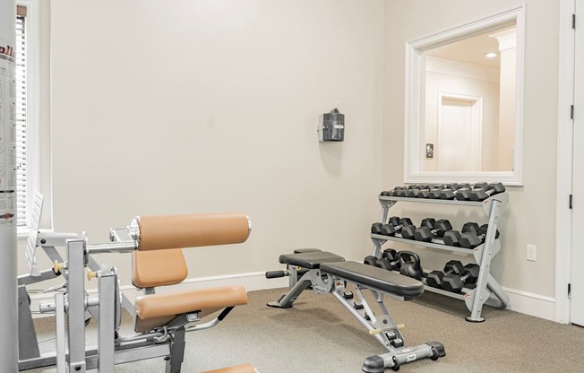 the gym with weights and chairs at the grove apartments