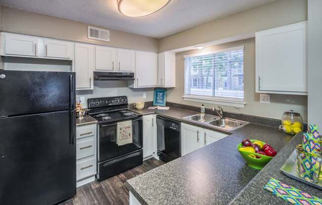 A black fridge and oven in a kitchen with white cabinets.