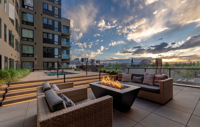 an outdoor patio with couches and a fire pit on a rooftop