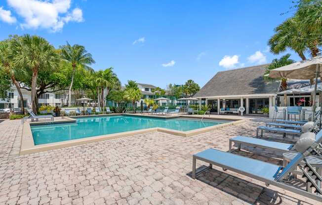 a swimming pool with lounge chairs and tables around it