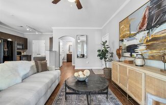 A living room with a grey couch, a black coffee table, and a painting on the wall.