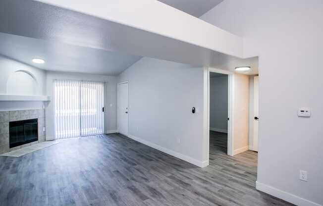an empty living room with a fireplace and hardwood floors