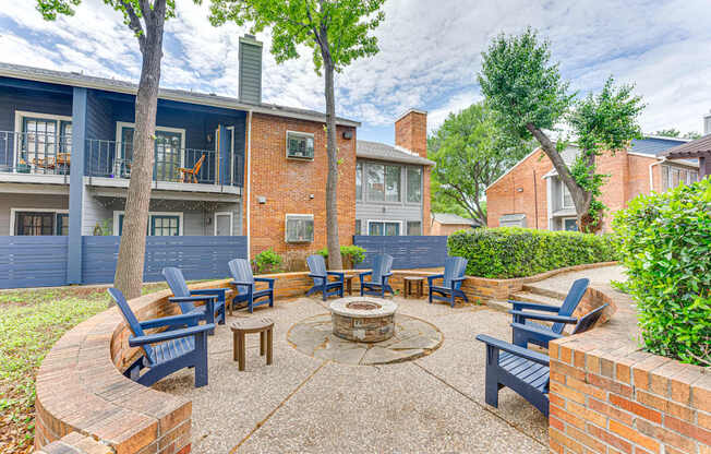A patio with a fire pit and chairs.