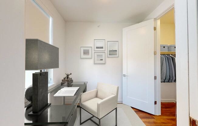 a living room with a desk and chair and a door to a closet