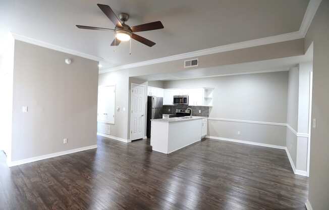 huge living area with dark wooden floors and white walls