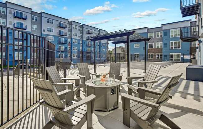 an outdoor patio with chairs and a fire pit and an apartment building