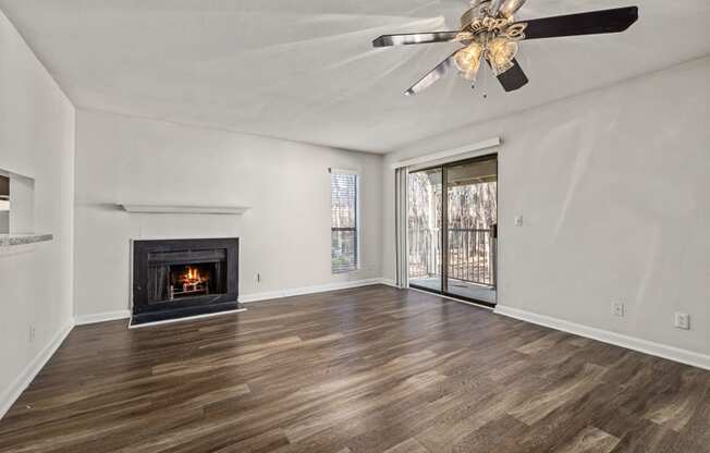 an empty living room with a fireplace and a ceiling fan