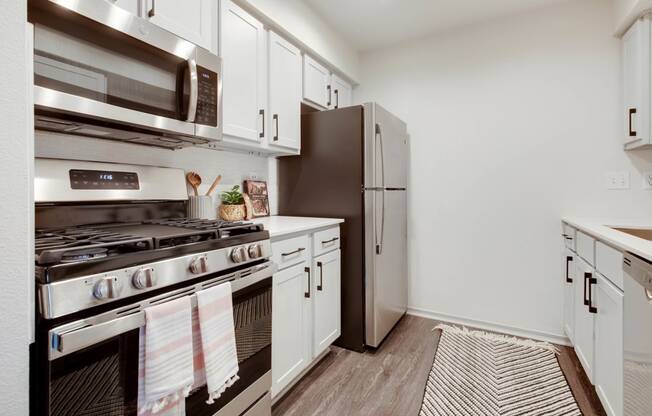 a kitchen with stainless steel appliances and white cabinets at The Olivine, Austin, 78727