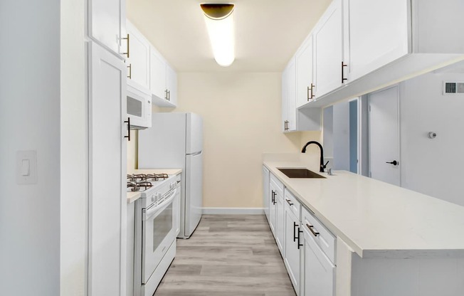 A kitchen with white cabinets and appliances.