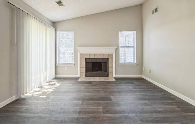 an empty living room with a fireplace and windows