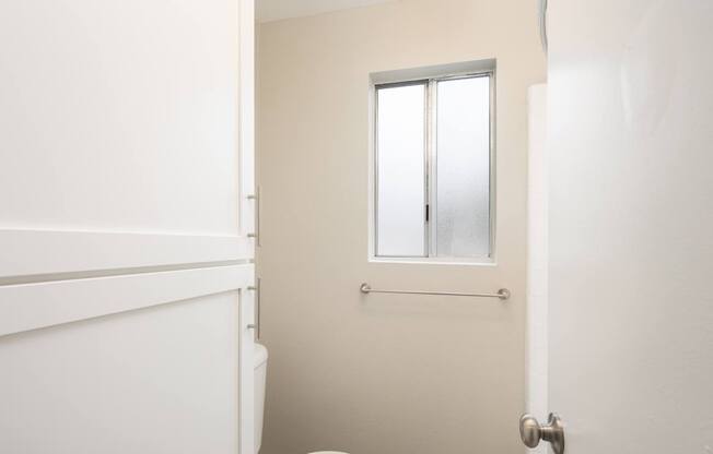 A white toilet sits in a bathroom with a door and a window.