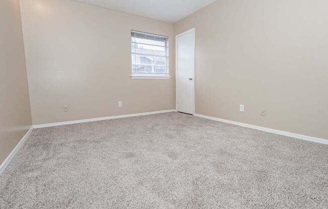 A bedroom with a carpeted floor and a closet  at The Creole Apartments in Shreveport, LA