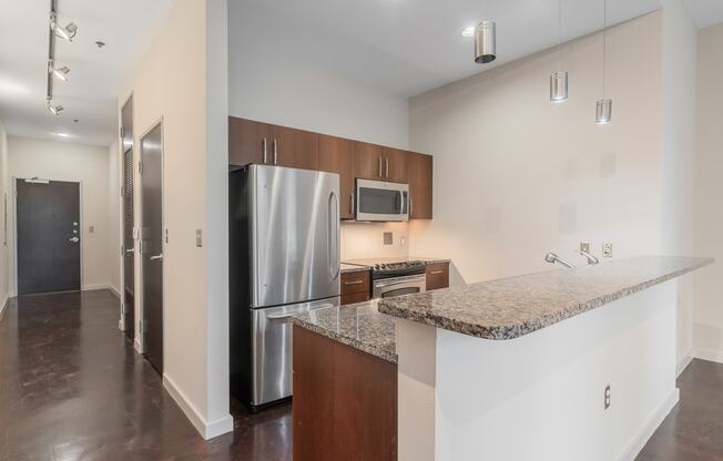 a kitchen with a granite counter top and a stainless steel refrigerator