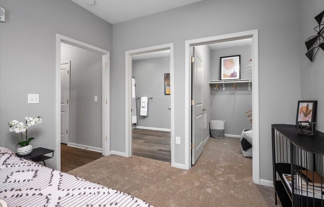 a bedroom with three doors open to a bathroom and a closet