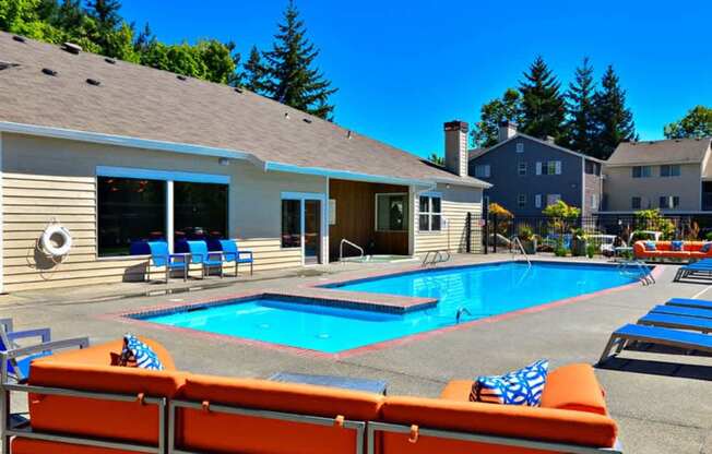 A poolside area with orange sun loungers and a clear blue sky.
