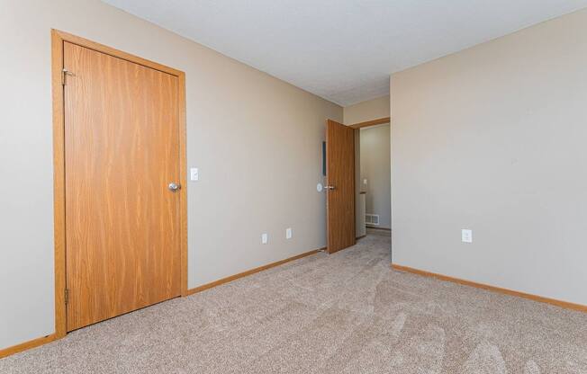 A room with a carpeted floor and two doors.