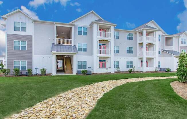 A large white apartment building with a stone pathway leading to the entrance.