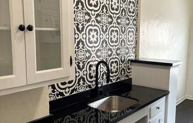 a black and white kitchen with a sink and white cabinets