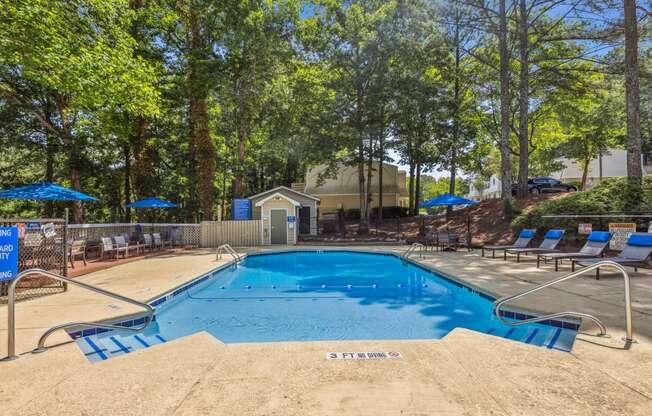 our resort style swimming pool is surrounded by chairs and trees