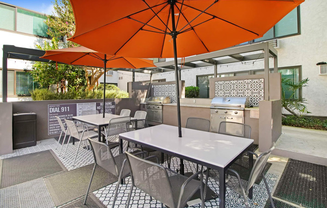 a patio with tables and chairs and an orange umbrella