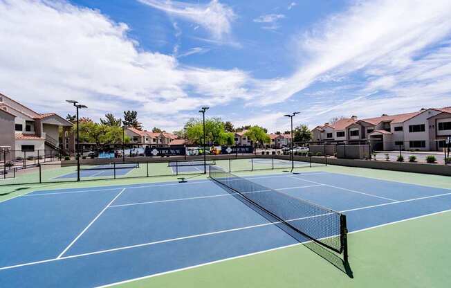 A tennis court with a blue surface and a green border.