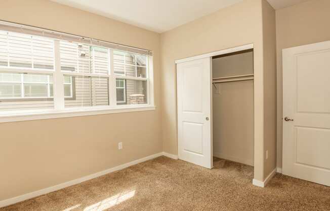 an empty bedroom with a window and a closet