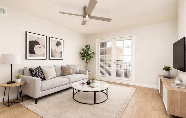 A living room with a grey couch, a coffee table, and a ceiling fan.