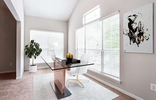 a home office with a large window and a large potted plant