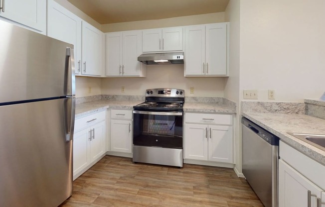 a renovated two bedroom kitchen with stainless steel appliances and white cabinets
