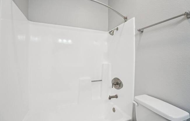 A white bathroom with a toilet and a shower.