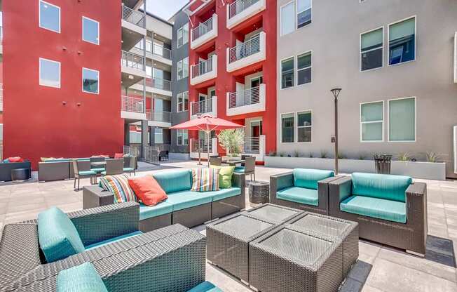 A patio with a couch, chairs, and a table with a glass top.