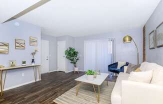 A living room with a white couch, a coffee table, and a blue chair.