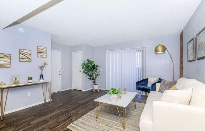 A living room with a white couch, a coffee table, and a blue chair.