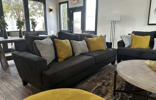a living room with a black couch and yellow pillows