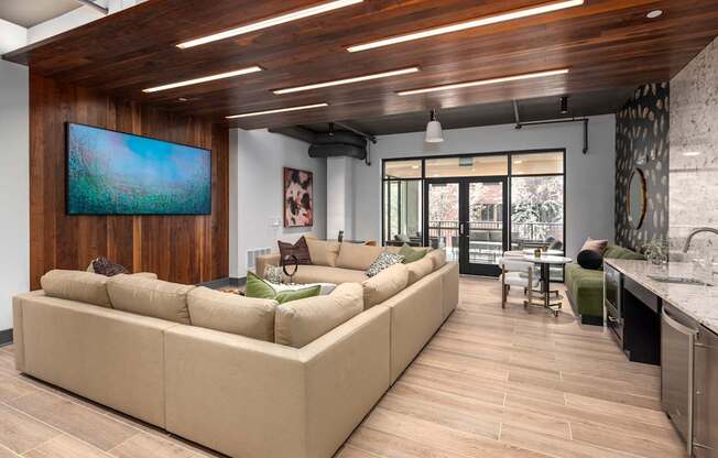 A modern living room with a large couch and a painting on the wall.