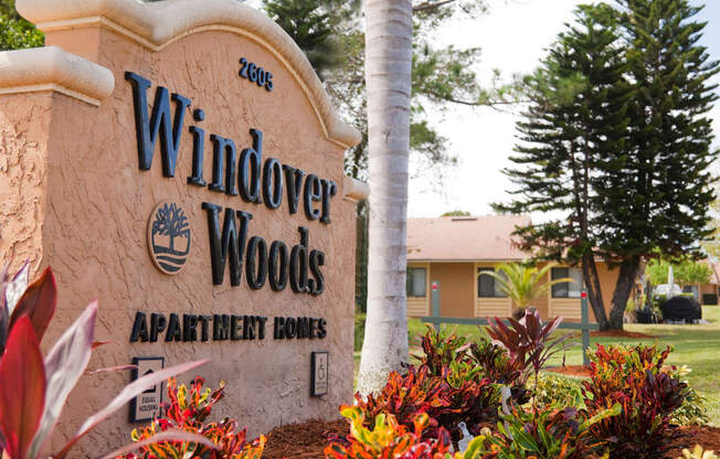 a sign for windsor woods apartments with a building in the background