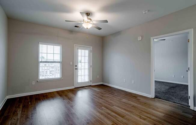 A room with a ceiling fan and wooden floors.