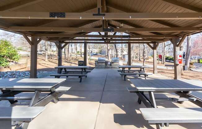 A covered picnic area with tables and benches at Madison Woods apartments in Greensboro, NC.